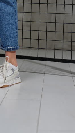 close-up of white sneakers on legs in jeans