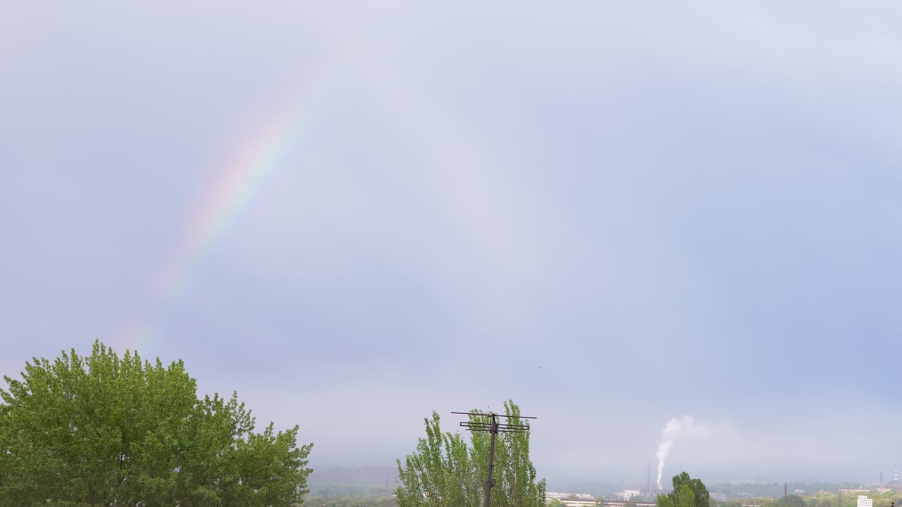 aparición de un fantástico arco iris brillante en el horizonte a través de nubes grises en el cielo. 4k