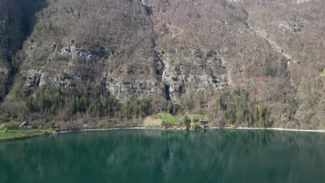 Drone-clip-showing-fresh-green-glacial-lake-water,-surrounded-by-steep-alpine-mountains