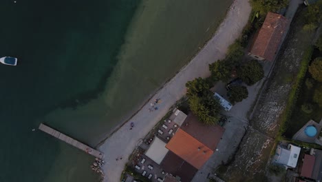 people resting on the promenade of salo town by lake garda, top view aerial