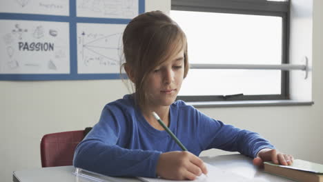 in school, boy writing with pencil in classroom, concentrating on work