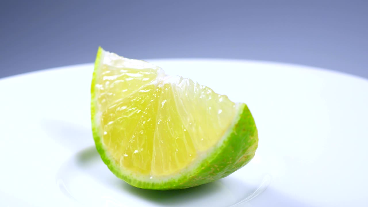 una rebanada de limón verde está girando lentamente en el estudio con los detalles.