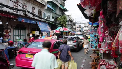 pedestrians and cars navigate a busy market street.