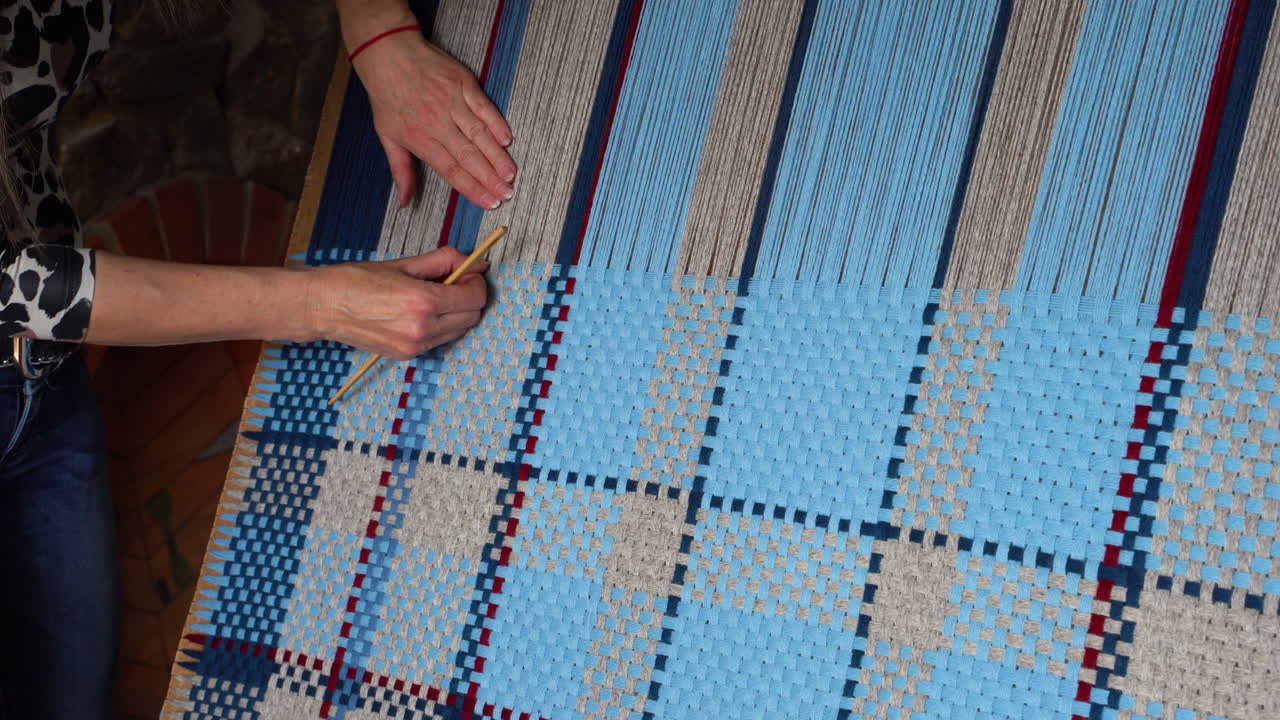 donna che lavora su un progetto di tessitura blu e beige, scatto panoramico