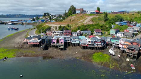 aerial view tilting over palafitos stilt houses on the shore of castro, chiloe