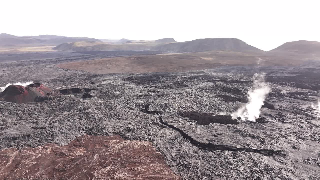 thick smoke rises from fissures in hardened lava across barren iceland
