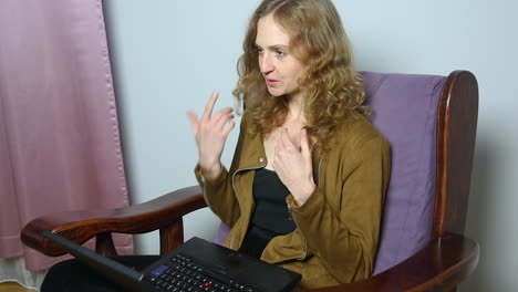 Young-cheerful-woman-doing-video-call-on-laptop-while-working-at-home