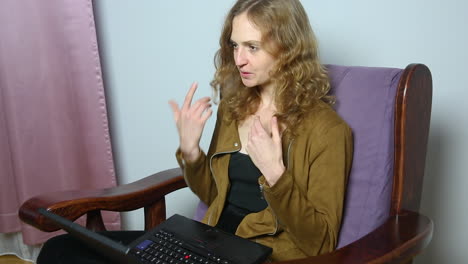 young cheerful woman doing video call on laptop while working at home