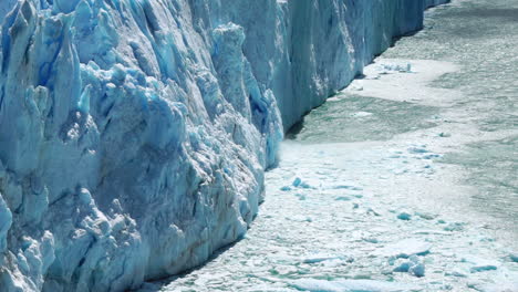 blue glacier melting with pieces of ice calving off, zoom in