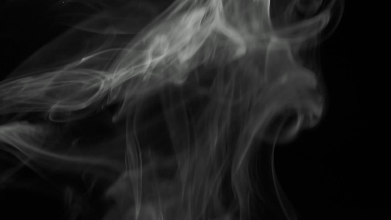 Sottile rivolo di fumo argenteo che sale lentamente con eleganti volute verso l'alto. Fumo di sigaro che si muove dal basso verso l'alto. Primo piano, isolato su sfondo nero
