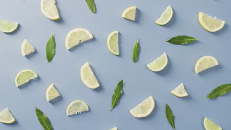 video of slices of lemon and mint leaves lying on blue background