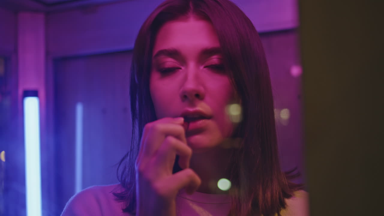 Neon brunette colouring lips standing call box closeup. Sad woman looking camera