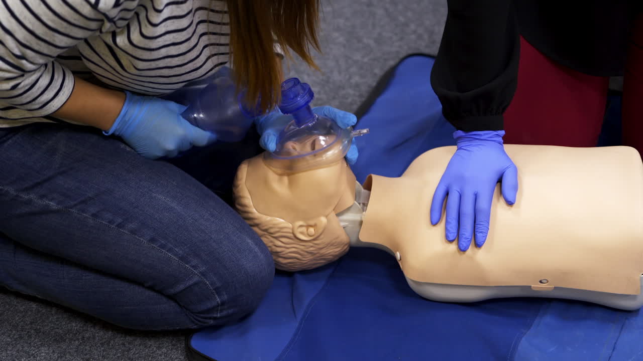 Training reanimation procedure on a mannequin. People use breathing apparatus on a dummy's face during practice course. Training for giving first aid to a patient.