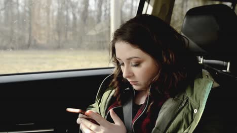 Una-Adolescente-Bastante-Joven-En-El-Asiento-Del-Pasajero-De-Un-Jeep-Enviando-Mensajes-De-Texto-A-Su-Teléfono-Celular-Y-Riéndose-De-La-Pantalla