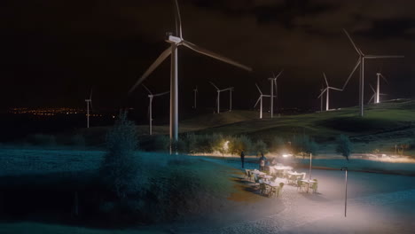 night view of a wind farm with an illuminated outdoor cafe