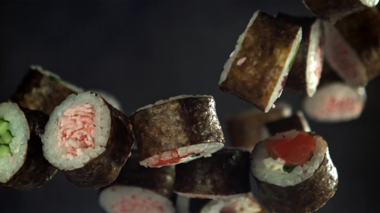 Roll di sushi maki giapponesi freschi che galleggiano su sfondo scuro
