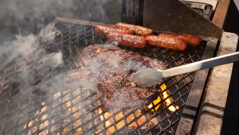 american bbq, large smoking steaks and sausage on a wooden grill