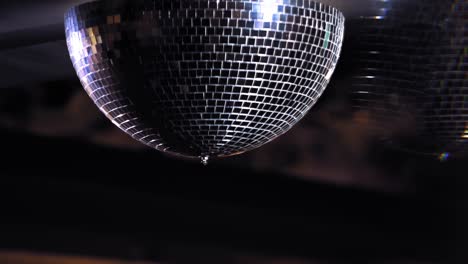 beautiful disco ball rotating with bright flares on black background. mirrorball spinning slowly reflecting club lights and lasers. close-up.