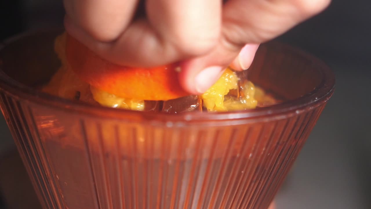 Mano che sprema succo d'arancia fresco con uno spremiagrumi manuale