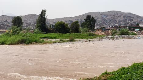 Muddy-polluted-waters-flow-through-the-Rimac-River-watershed-in-Lima,-Perú-2023