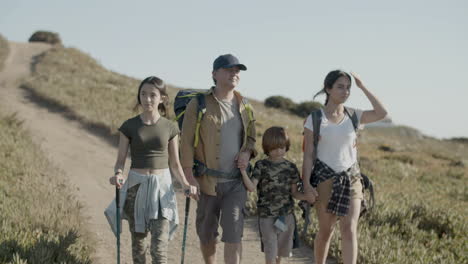 father and children backpacking together, walking along path and enjoying the view