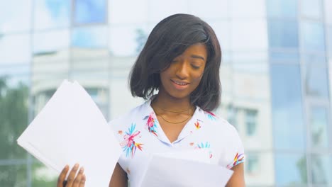 adult african american young business woman works with documents near modern office building