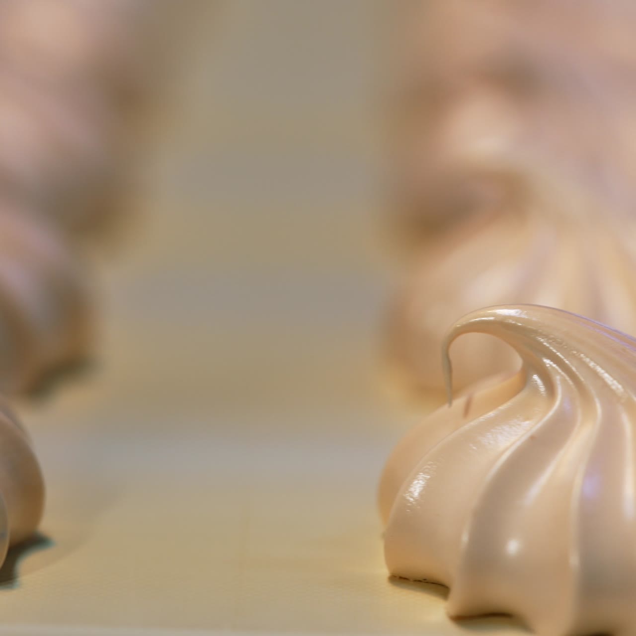 Freshly-made marshmallows on the belt of conveyor. White soufflé desserts close up. Blurred backdrop