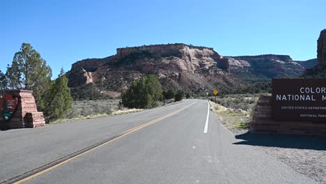 Standing-in-front-of-the-Colorado-National-Monument-sign-in-Fruita-Colorado,-Pan