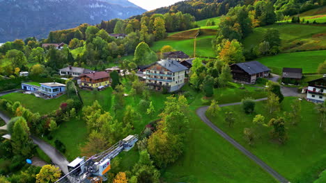 Drone-flies-past-construction-crane-up-into-green-hillside-with-cute-European-home