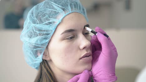la niña se somete a un procedimiento de maquillaje permanente de las cejas