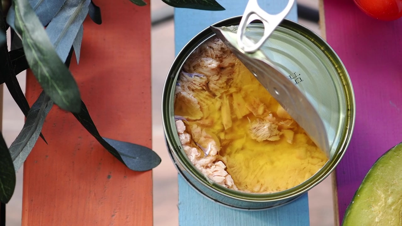 Lattina aperta di tonno sott'olio con avocado fresco e pomodori