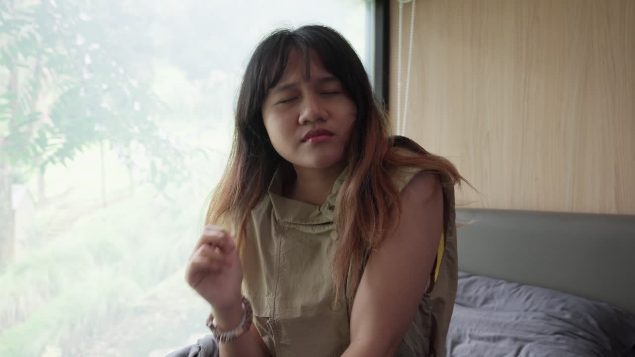 Indonesian woman waking up, stretching and opening her eyes