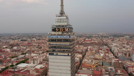 Al-Revés-Revelan-Los-Alrededores-Del-Edificio-Alto-Torre-Latinoamericana.-Cámara-Volando-Alrededor-De-La-Parte-Superior-Del-Rascacielos,-Paisaje-Urbano-En-Segundo-Plano.-Ciudad-De-México,-México.