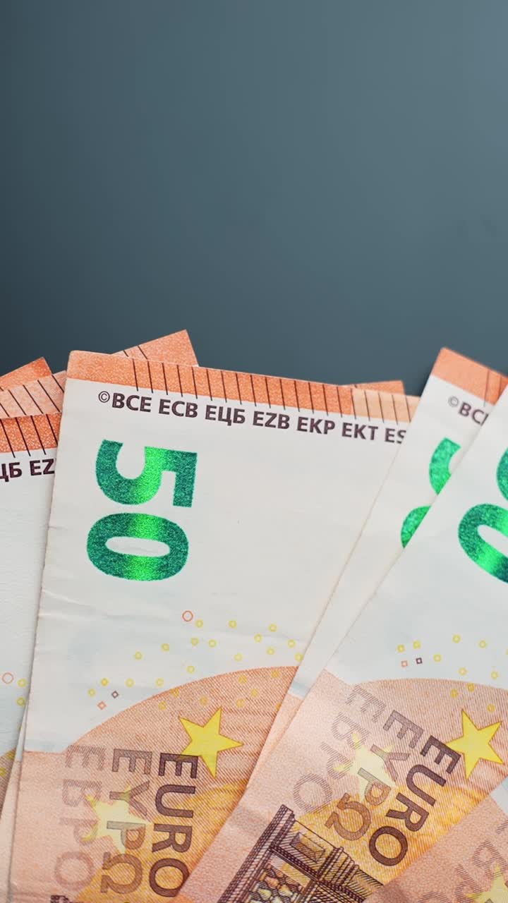 Vertikale Nahaufnahme von 50-Euro-Banknoten, die sich langsam auf einer dunklen Tischplatte mit weichem Bokeh und Leerraum drehen und Finanzen, Sparen sowie Zahlungen symbolisieren.