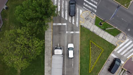 video de drone 4k de arriba hacia abajo, mirando hacia abajo a los autos en una calle que comienzan a conducir hacia un cruce de calles y el dron los sigue