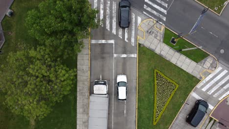 drone 4k top down video, looking down on cars in a street starting to drive forward to a street crossing and drone follows