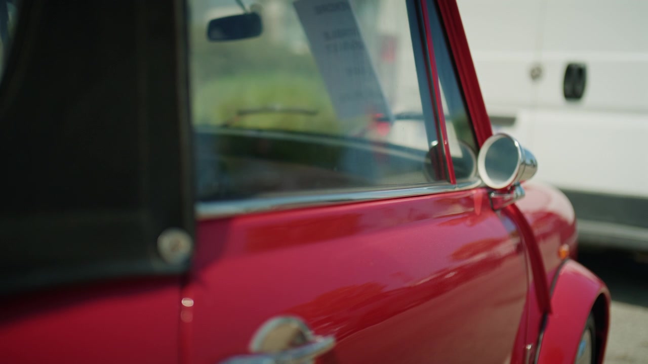 Close-up de retrovisor de carro clássico vermelho vintage e carroceria brilhante com profundidade de campo rasa e reflexos suaves da luz do sol