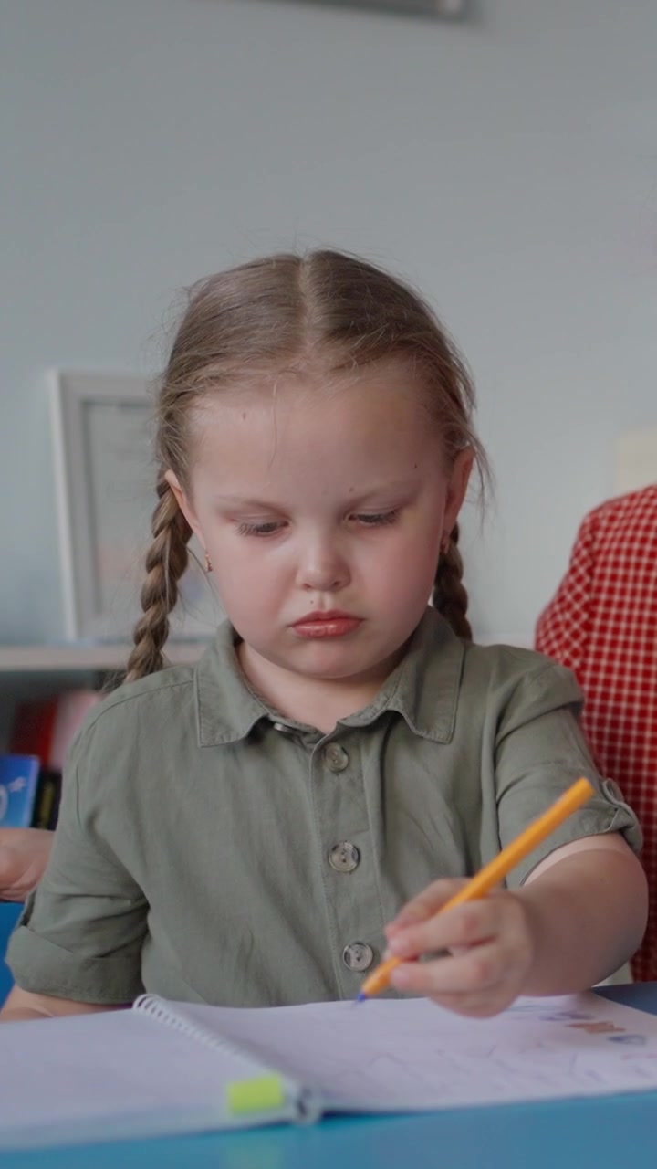 Giovane ragazza con le trecce concentrata mentre scrive su un quaderno