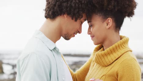 close up of african american couple dancing together on the rocks near the sea