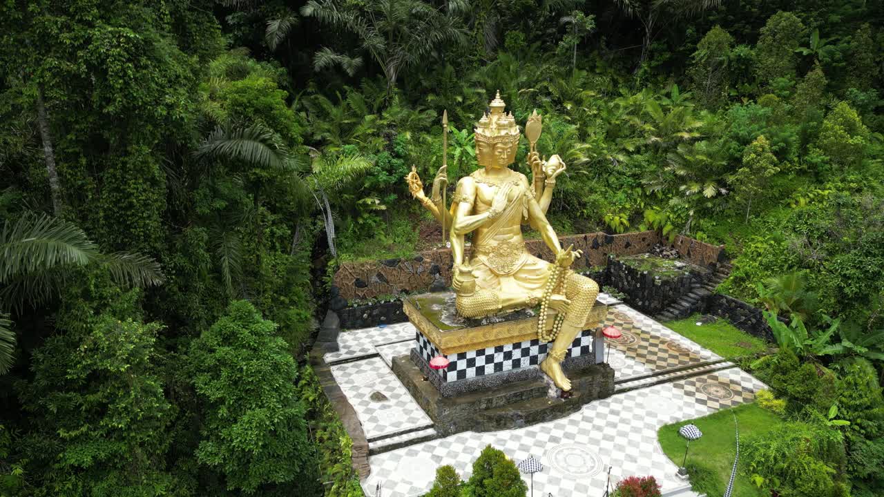 estatua de oro de buda en el este de bali, rodeada de una exuberante selva verde, aérea