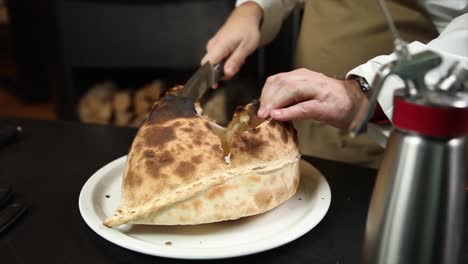 chef cutting a large, open-faced pizza bread