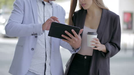 male and female colleagues using tablet pc outdoor