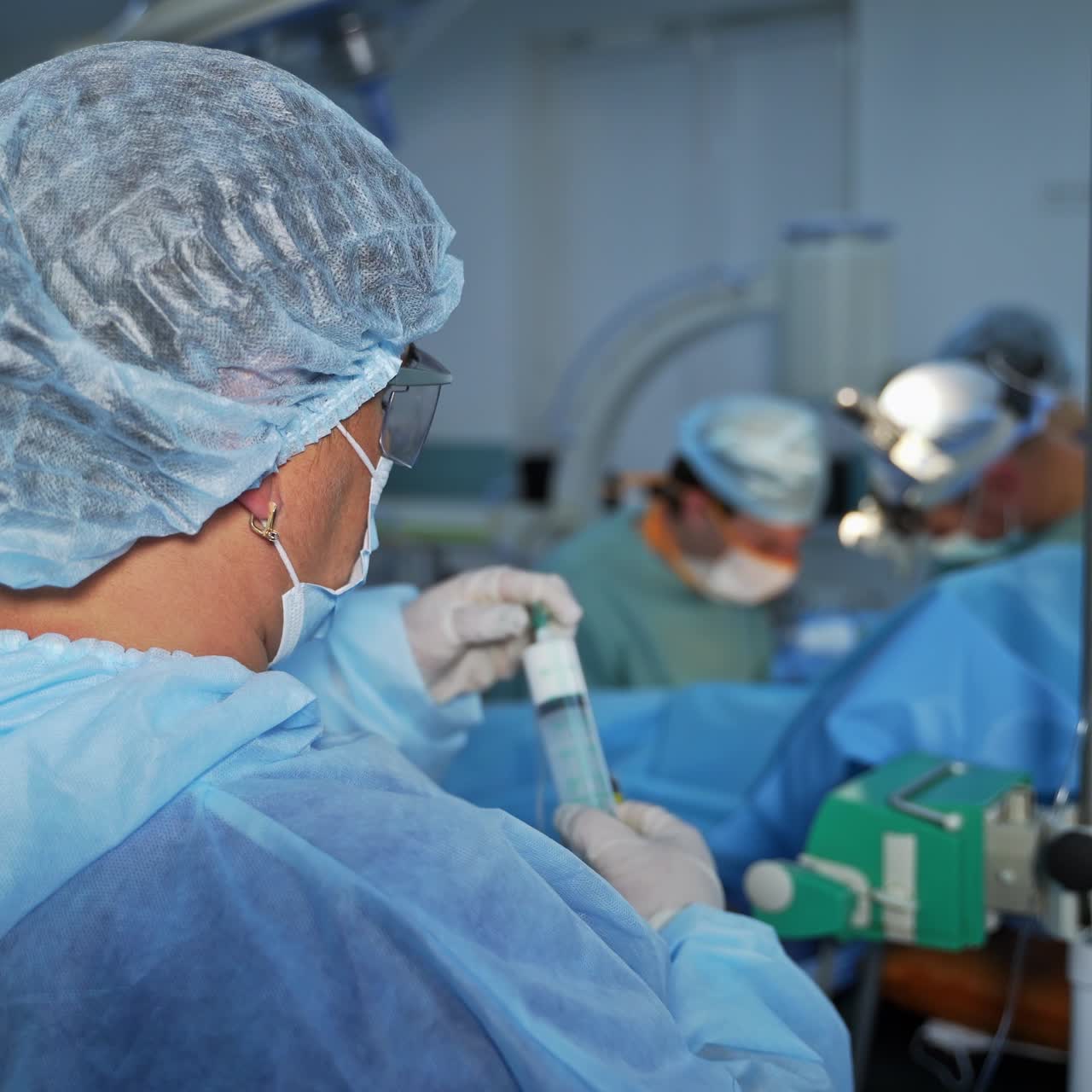 Surgical nurse preparing medicines necessary for operation. Female assistant changes smaller syringe into bigger one, filled with white stuff