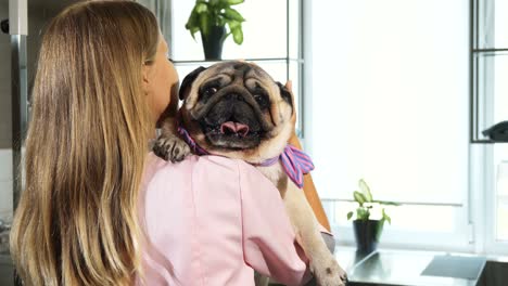 la joven enfermera está abrazando al perro pug