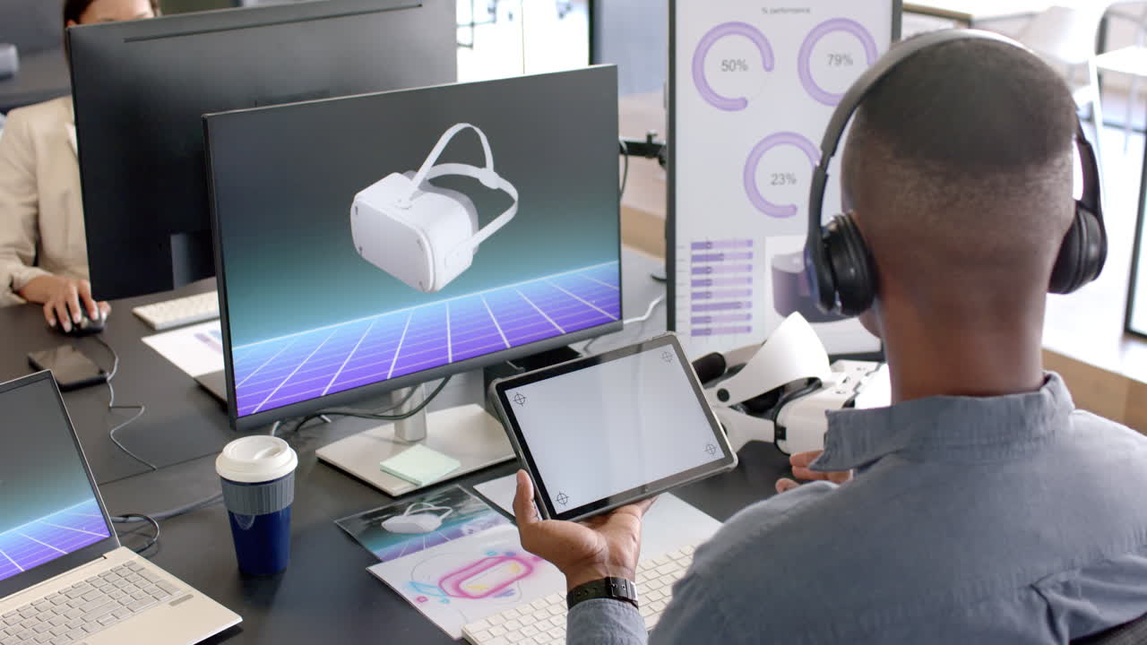 Using tablet and VR headset, African American man working on virtual reality design in office