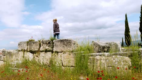 female visitor explores ancient large stones of ruined roman city hierapolis