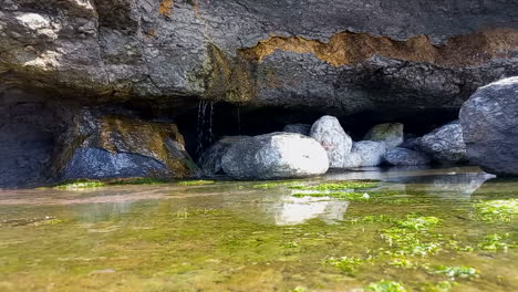 Wasser,-Das-Durch-Die-Felsen-Fiel,-Bildet-Eine-Wasserschicht-In-Den-Höhlen-Am-Hang-Neben-Dem-Meer