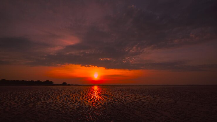 Time lapse of the Wadden Sea sunset at Hooksiel, North Germany with clouds sky moving and reflection