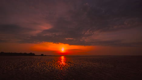 Zeitraffer-Des-Sonnenuntergangs-Am-Wattenmeer-Bei-Hooksiel,-Norddeutschland-Mit-Bewegten-Wolken-Und-Spiegelungen-Am-Himmel