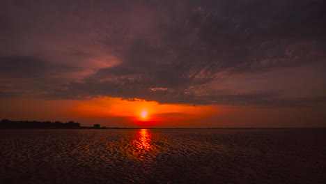el lapso de tiempo de la puesta de sol del mar de wadden en hooksiel, alemania del norte con nubes cielo en movimiento y reflejo